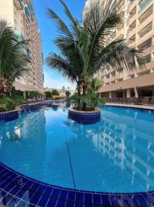 Olímpia Park Resort à 50m do Thermas dos Laranjais في أوليمبيا: مسبح كبير فيه نخلة امام مبنى