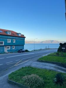 an empty road next to a building and the ocean at Apartamento Finisterrae in Fisterra