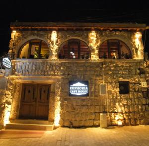 een stenen gebouw met 's nachts een bord bij Euphoria Cave House in Nar