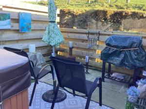 un patio con sedie, ombrelloni e tavolo di Adorable private couples retreat with hot tub a Llanfechell