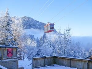 a ski lift in the air with snow covered trees at La Ferme du Golf in Megève