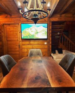 a dining room with a large wooden table and a television at DAJTI PARADISE RESORT in Tirana