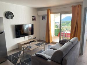 een woonkamer met een bank, een televisie en een balkon bij T2 Saint-Mandrier-sur-Mer in Saint-Mandrier-sur-Mer