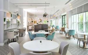 uma sala de jantar com mesas, cadeiras e janelas em Hilton London Croydon em Croydon