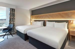 a hotel room with two beds and a desk at Hilton London Croydon in Croydon