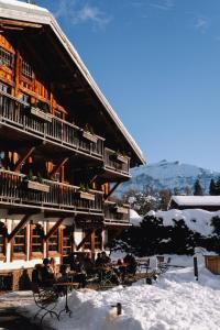 a group of people sitting outside of a building in the snow at La Ferme du Golf in Megève