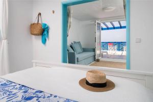 einen Hut auf einem Bett vor einem Spiegel in der Unterkunft Casa Charcón Alto, en primera línea de mar - Best Villas Lanzarote in Famara