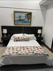 1 dormitorio con 1 cama blanca grande y 2 lámparas en Porto Bello Hotel Boutique, en Puerto Colombia