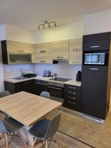 a large kitchen with a wooden table and chairs at TriAngol Apartman: fürdő, belváros, egyetem in Győr