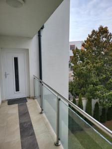 d'un balcon avec une balustrade en verre et une porte. dans l'établissement TriAngol Apartman: fürdő, belváros, egyetem, à Győr