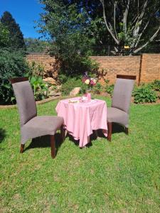 two chairs and a table with a pink table cloth at La Cheteau B&B in Springs