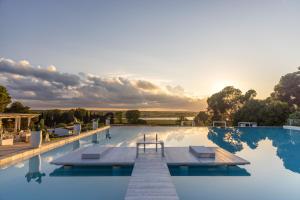 ein Swimmingpool mit einem Sonnenuntergang im Hintergrund in der Unterkunft Baglioni Masseria Muzza Resort & Spa in Otranto