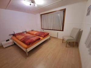 ein Schlafzimmer mit einem Bett, einem Stuhl und einem Fenster in der Unterkunft Ferienwohnung Brüstiblick in Attinghausen
