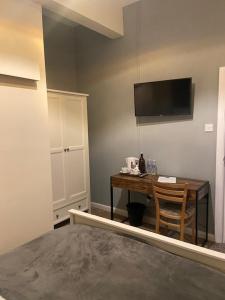 Zimmer mit einem Schreibtisch und einem TV an der Wand in der Unterkunft The Tavern in Matlock