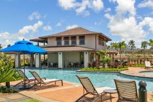 a house with a pool with chairs and an umbrella at 3 Bedroom 3 Bathroom Condo with Ocean View - Alekona Kauai in Koloa