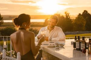 um homem e uma mulher sentados numa mesa com garrafas de vinho em Baglioni Masseria Muzza em Otranto