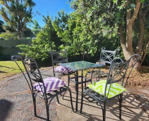 Quirky Villa في وانغانوي: ثلاثة كراسي وطاولة مع غطاء زجاجي