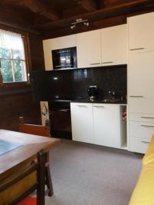 a kitchen with white cabinets and a wooden table at Chalet Holzwurm in Oberried