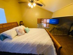 The Overlook~Bandera, TX في بانديرا: غرفة نوم بسرير أبيض مع مروحة سقف