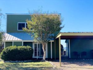 a green house with a tree in front of it at The Overlook~Bandera, TX in Bandera