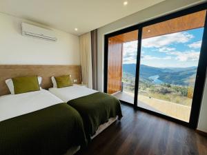 a bedroom with two beds and a large window at Encosta do Gerês Village in Ventosa