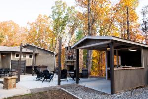 un patio cubierto con parrilla, mesas y sillas en New Listing! Three Chimney Lodge - 4 Bed, Hot Tub, en Dahlonega