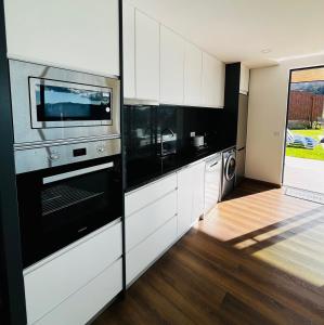 a kitchen with white cabinets and black appliances at Encosta do Gerês Village in Ventosa