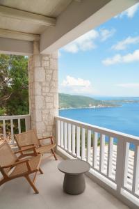 a balcony with chairs and a table and the ocean at Urania Luxury Villa Rhea in Póndi