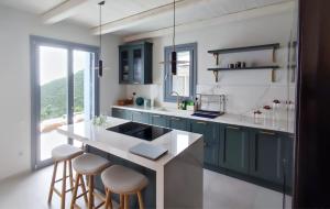 a kitchen with blue cabinets and a counter with stools at Urania Luxury Villa Rhea in Póndi