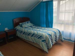 a bedroom with a bed with blue walls and a window at hospedaje 12 de octubre in Coihaique