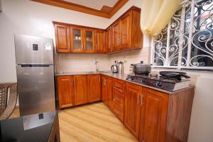 a kitchen with wooden cabinets and a stainless steel refrigerator at Kibibi Lake view furnished suites in Wakiso