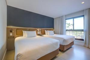 a hotel room with two beds and a window at Hilton Garden Inn São José do Rio Preto in Sao Jose do Rio Preto