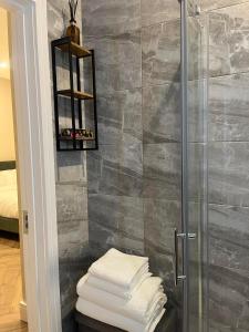 ein Bad mit einer Dusche und einem Stapel Handtücher in der Unterkunft Attic Room in Citywest in Dublin