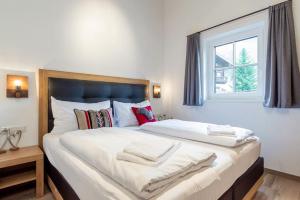 duże białe łóżko w pokoju z oknem w obiekcie Wasserfall Lodge Krimml w mieście Krimml
