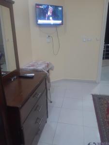 a room with a tv on a wall with a dresser at Kazpilkna Beach Neighborhoods in Hurghada