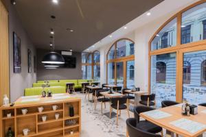 a restaurant with tables and chairs and windows at Hotel Urban in Baia Mare