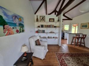sala de estar con silla blanca y mesa en Sitio Carpir - conforto, charme e natureza a 2h de SP, en Paraibuna