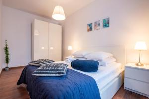 een slaapkamer met een groot wit bed met blauwe lakens en kussens bij City Lights Bosacka in Krakau
