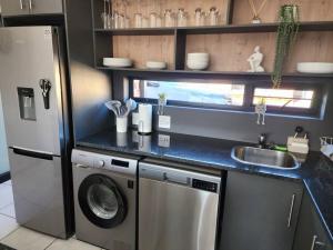 eine Küche mit einer Waschmaschine und einem Waschbecken in der Unterkunft Home@Micasa Unit 95 in Potchefstroom