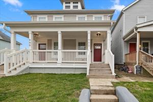 a house with a white porch with a red door at Centrally located renovated home in Columbus