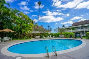 a swimming pool in a resort with chairs and a palm tree at Plantation Hale J11 in Kapaa