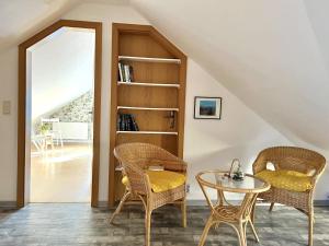 een kamer met 2 stoelen, een tafel en een boekenplank bij Dat Dörphuus in Krummhörn
