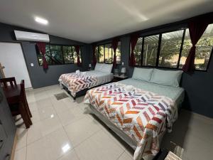 2 camas en una habitación con ventanas en El mangal B&B, en Suchitoto