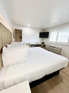 ein Schlafzimmer mit einem großen weißen Bett mit weißen Kissen in der Unterkunft Francisco Bay Inn in San Francisco