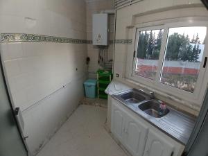 eine kleine Küche mit einem Waschbecken und einem Fenster in der Unterkunft Sunny Inn Les berges du lac 1 in Tunis