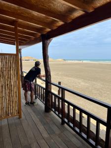 a man standing on a porch looking at the beach at Aloha Lobitos in Lobitos