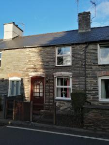 a brick house with a red door on a street at 2 Rhys Terrace in Machynlleth