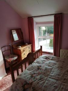 a bedroom with a bed and a dresser and a window at 2 Rhys Terrace in Machynlleth
