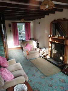 sala de estar con 2 sillas y chimenea en 2 Rhys Terrace en Machynlleth