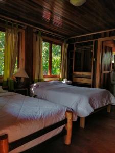 a bedroom with two beds and a tv and windows at Refugio de Orquídeas in Oxapampa